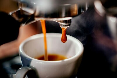 Commercial espresso machine dispensing into white mug