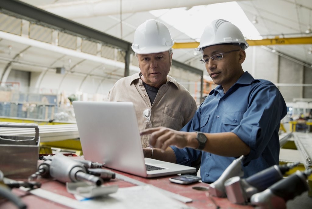 Two men discussing something in front of laptop