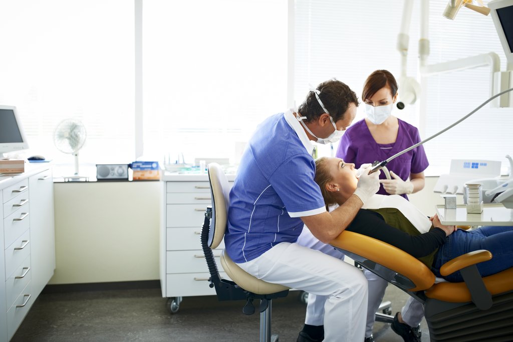 Un dentiste qui réalise une intervention sur un patient.