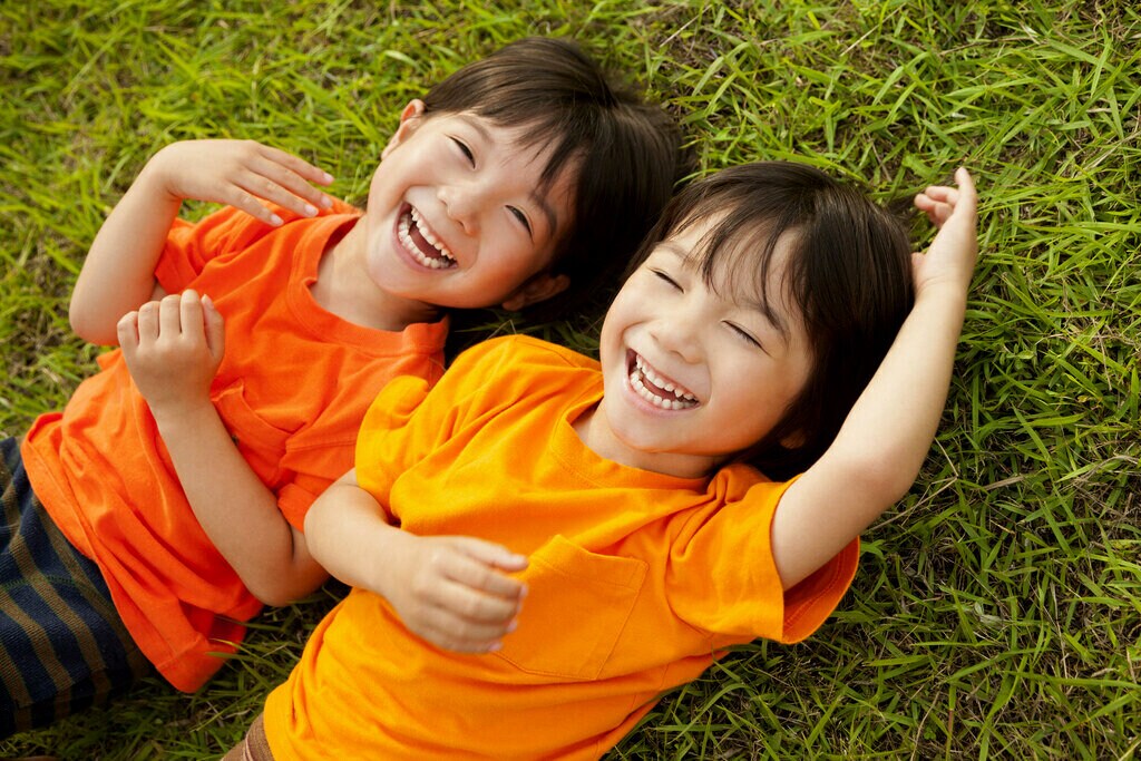 Deux enfants allongés dans l'herbe, souriant.