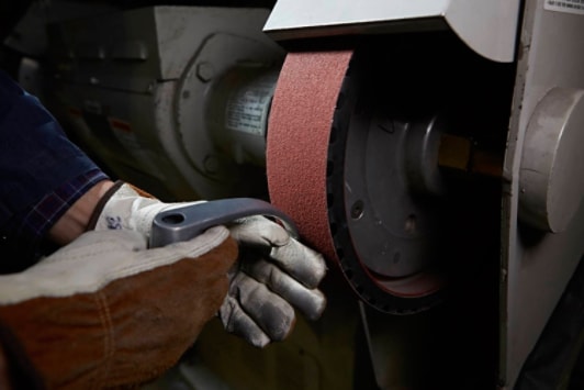 Metalworker grinding metal on an abrasive belt