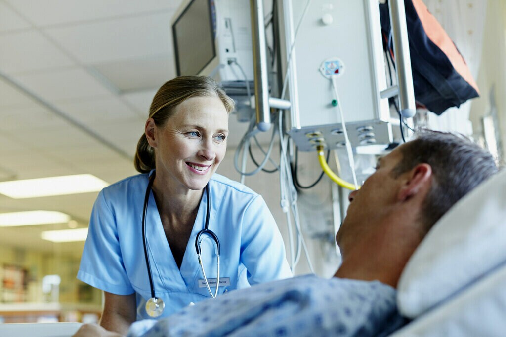 Docteur qui sourit au chevet d’un patient