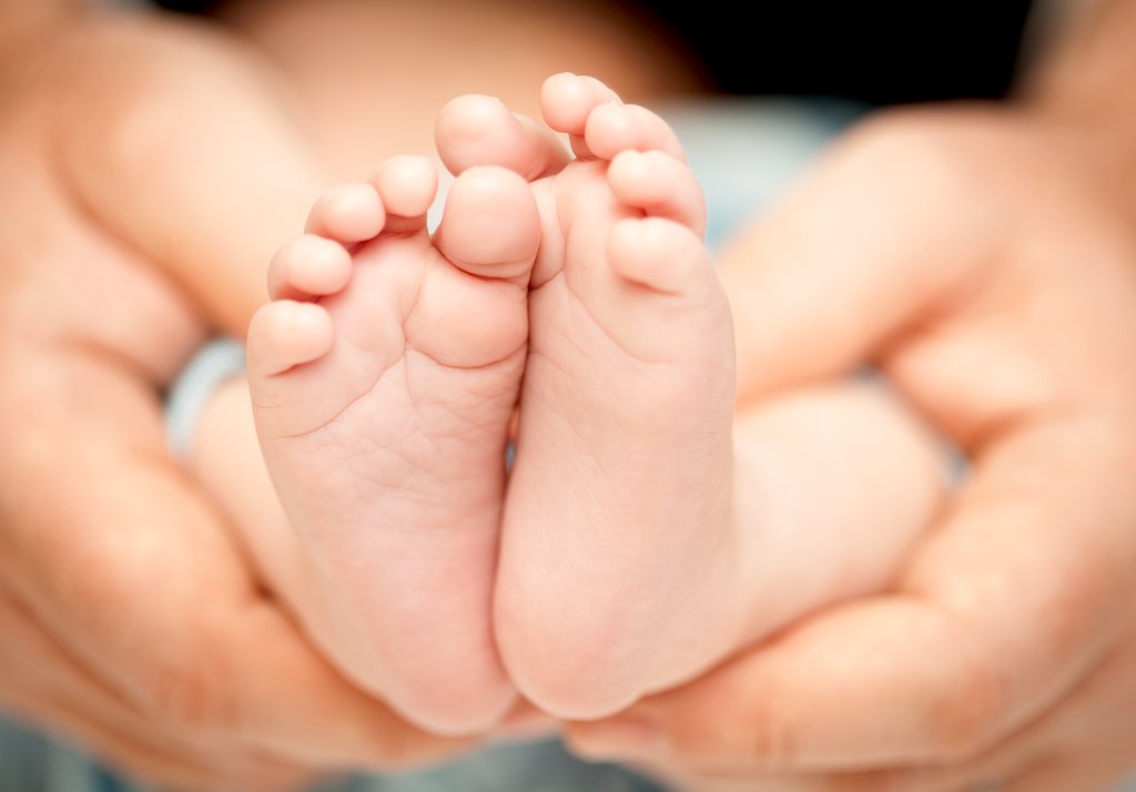 Adult hands holding a baby's legs