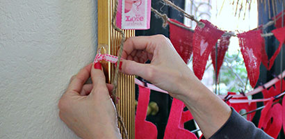 two hands tying end of garland to hooks on the frame of the larger mirror