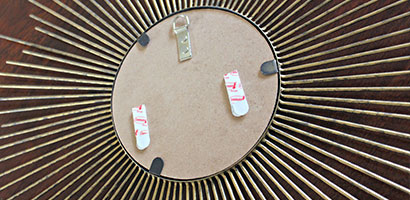 back of sunburst mirror with 2 stabilizer strips attached