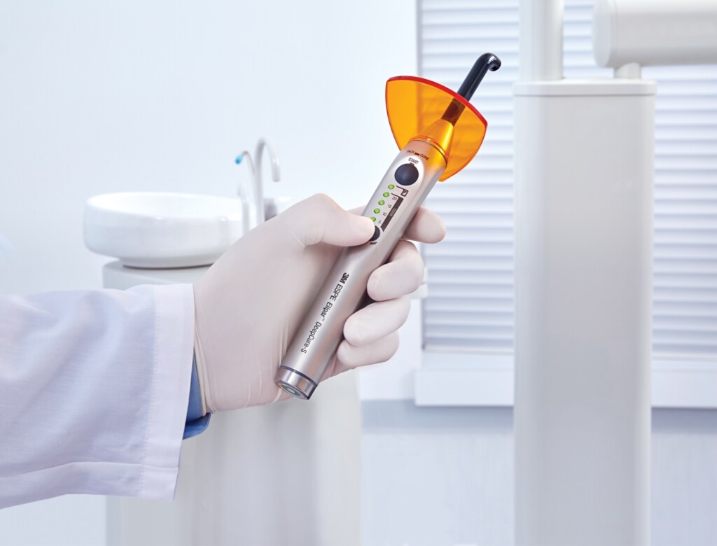 Dentist’s hand holding curing light  