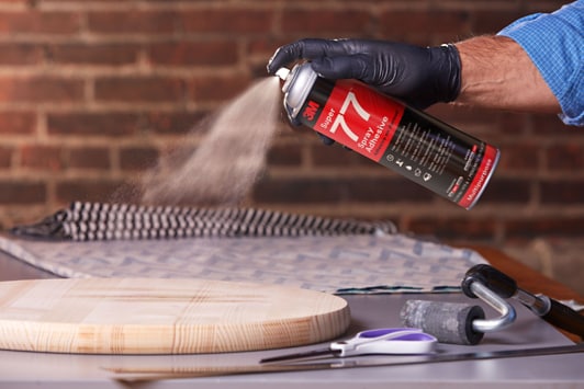 Image of a worker spraying a round wooden board