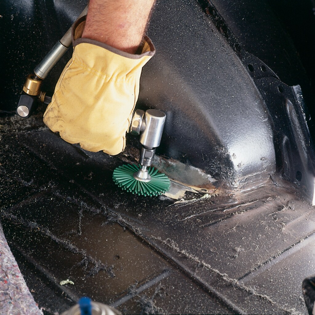 Man wearing personal protective equipment glove using an abrasive.