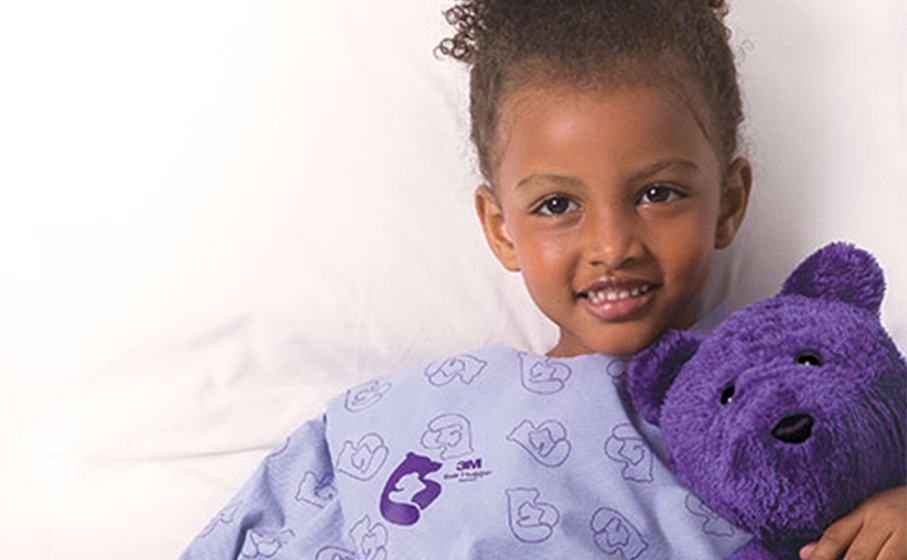 young patient wearing patient warming and holding teddy bear