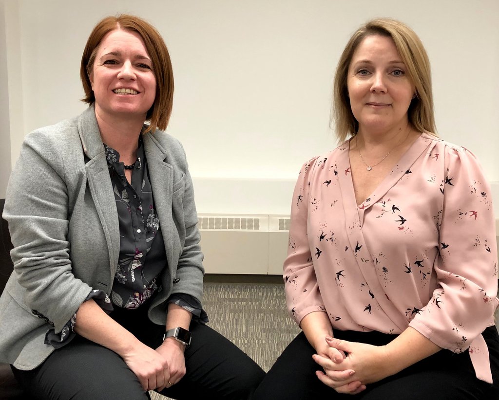 Deux femmes membres du groupe de ressources aux employés « Les capacités avant tout » assises ensemble et souriantes