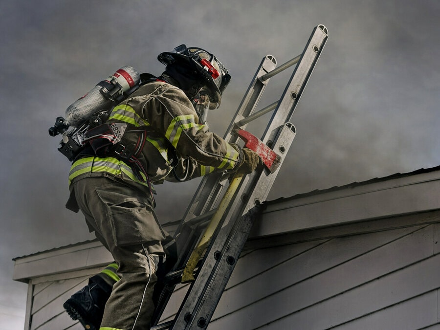 A firefighter climbing a ladder toward a fire