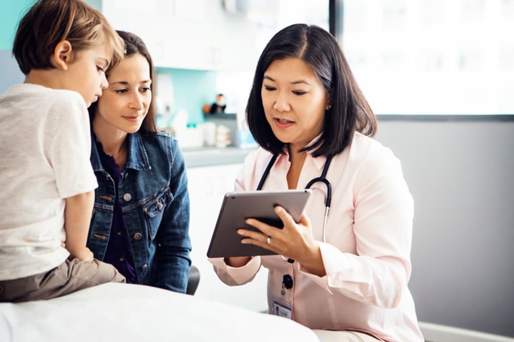 Médecin montrant sa tablette à une mère et son fils