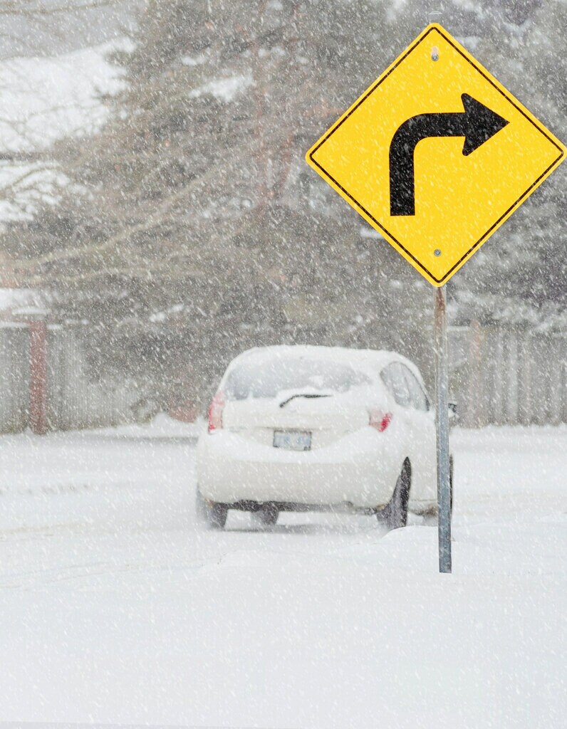 Voiture dans des intempéries, panneau de signalisation fluorescent sur la route.