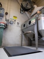 Image of duct tape holding down the edges of a padded floormat in front of an industrial machine