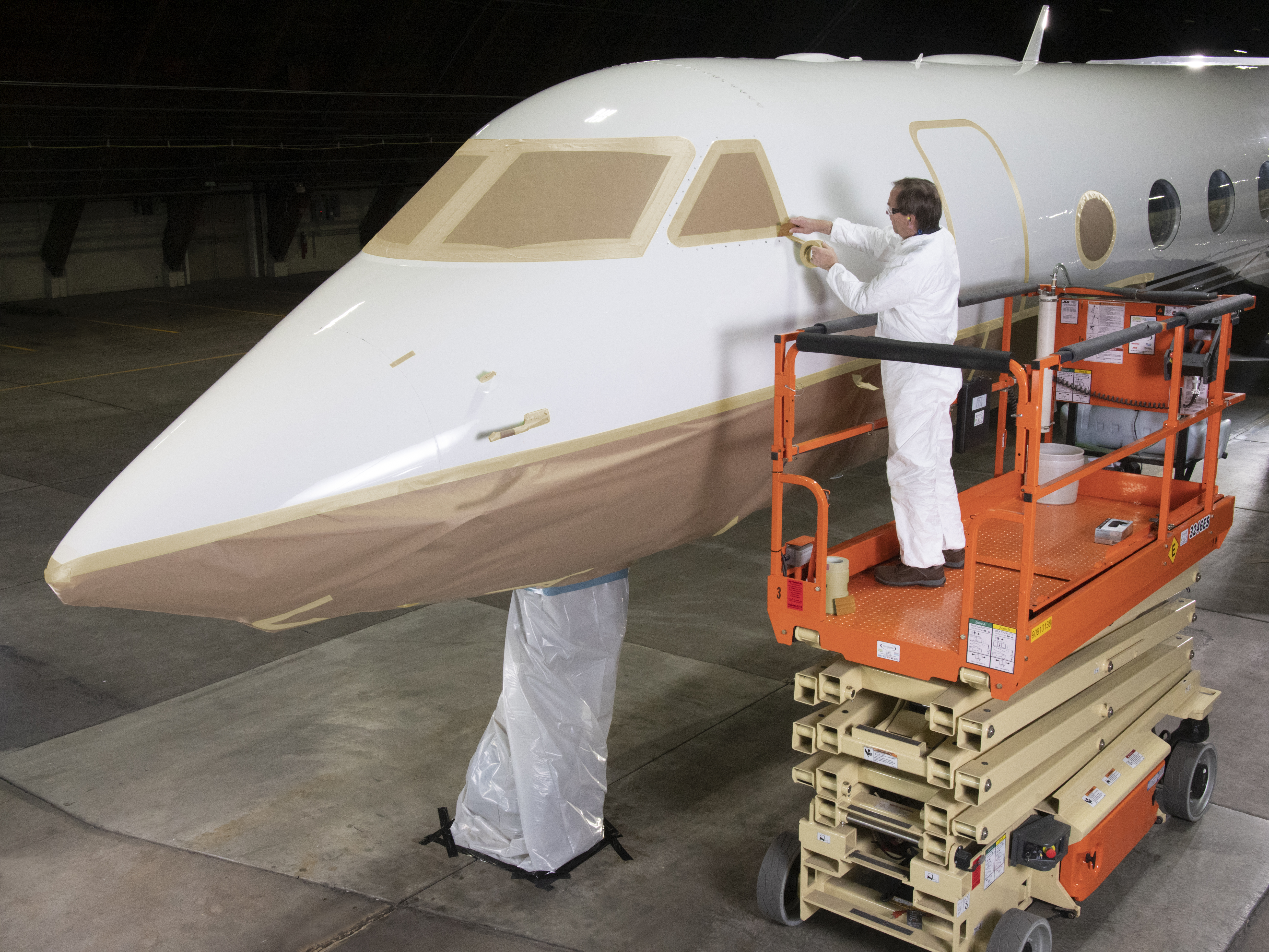 Image of a worker masking the exterior of an airplane cockpit