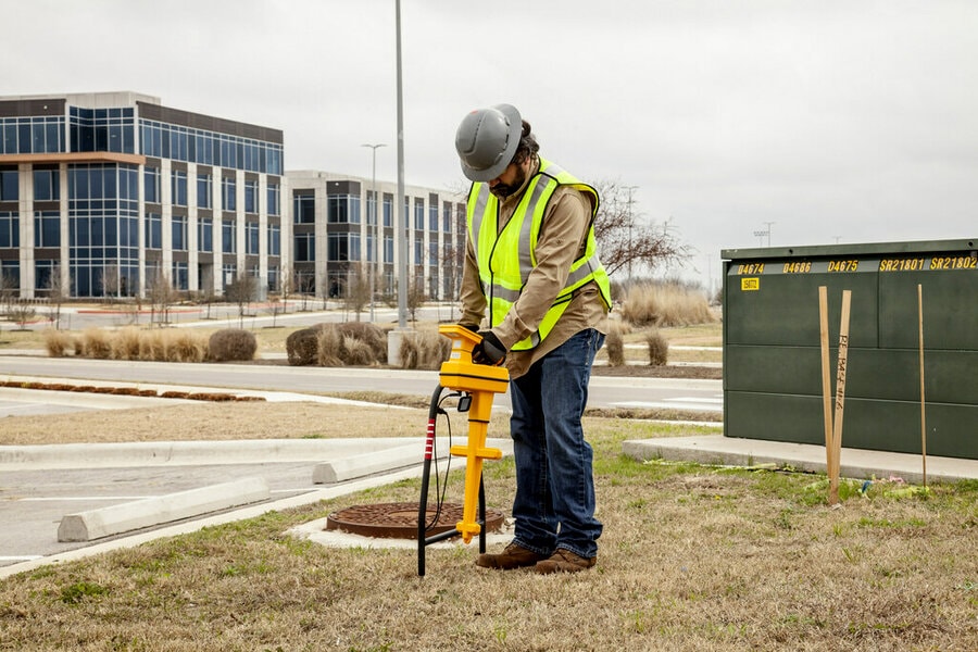 Worker outside in safety gear using yellow locator