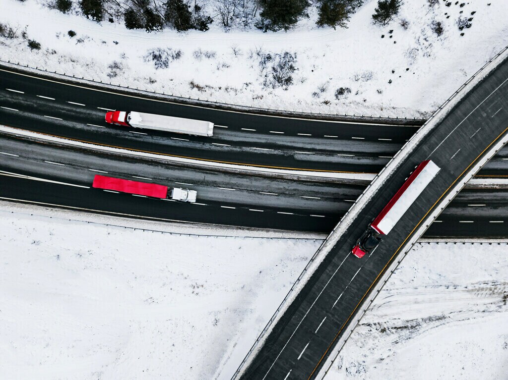 Three trucks heading in different directions on an overpass and highway.