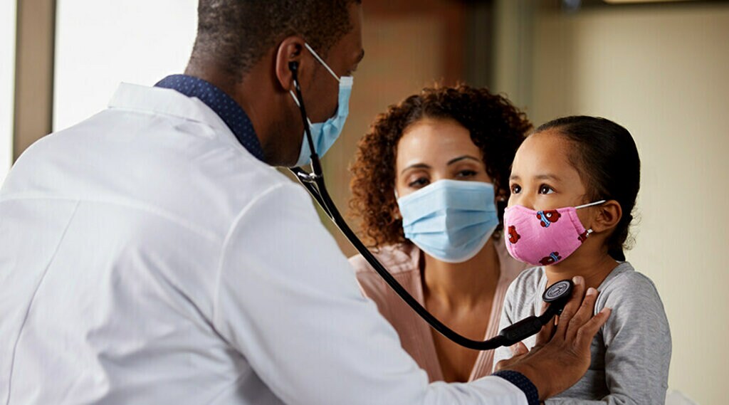 Un médecin noir tenant un stéthoscope numérique CORE Littmann pour écouter le battement de cœur d’une jeune fille noire.  