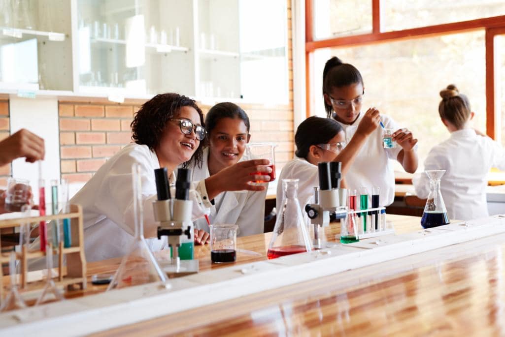 A group of individuals wearing white lab coats are engaged in a science experiment.