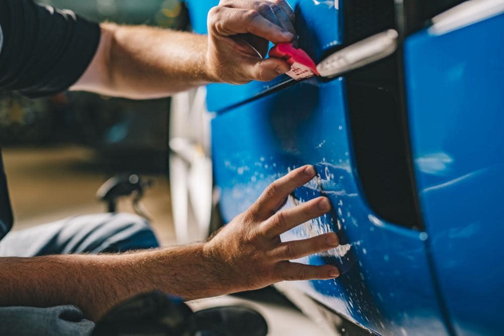 Professional installer applying paint protection film to a vehicle