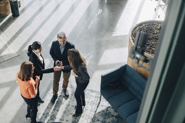 Three business professionals are engaged in a meeting, with two of them shaking hands, indicating a formal greeting or agreement.