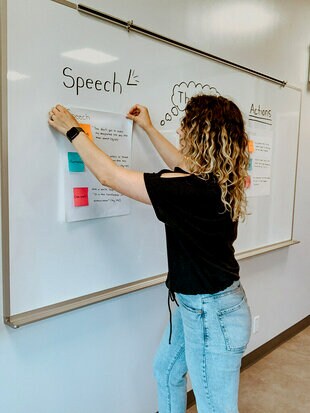 A teacher sticking a Post-it® Super Sticky Mini Easel Pad paper onto a whiteboard.