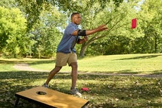 Man playing cornhole wearing ACE adjustable elbow support.
