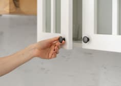 A person's hand is shown closing a cabinet door.