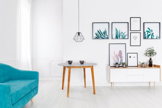 Grey chairs at wooden table and hanging lamp in living room interior with blue sofa and gallery.