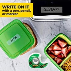 A top down view of a kitchen table showing plastic lunch containers and a label created with Scotch Magic Tape on a green plastic bin top reading 'jack',. The graphic overlay reads 'Write on it with a pencil, pen or marker'