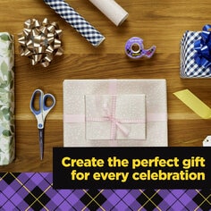 Scotch Gift Wrap Tape helps you create the perfect gift for every celebration.  A table is filled with wrapping paper, a bow, scissors, Scotch Gift Wrap tape and wrapped gifts.