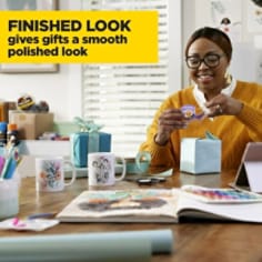 Scotch Gift Wrap Tape gives gifts a smooth polished look. A woman is wrapping gifts at a table. 
