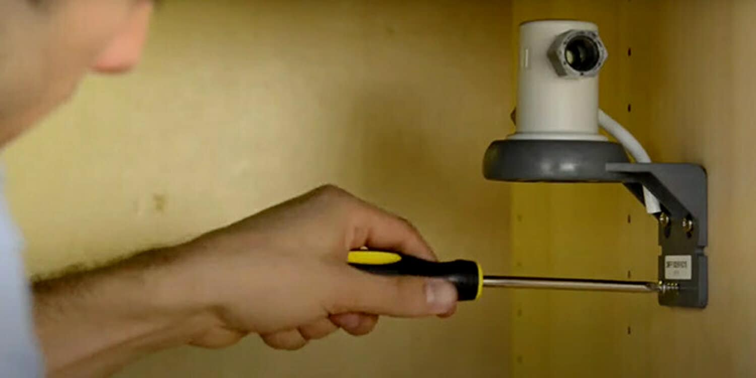 Image of someone fastening filter head wall fasteners into the wall