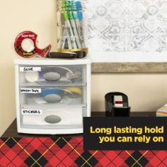 Scotch Super Hold Tape, long lasting hold you can rely on.  Image of tape on top of craft supply box in a home office.