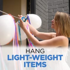 Scotch Wall Safe Tape, hang light-weight items, image of woman hanging a garland of balloons and streamers on a wall with Scotch-Wall Safe Tape.
