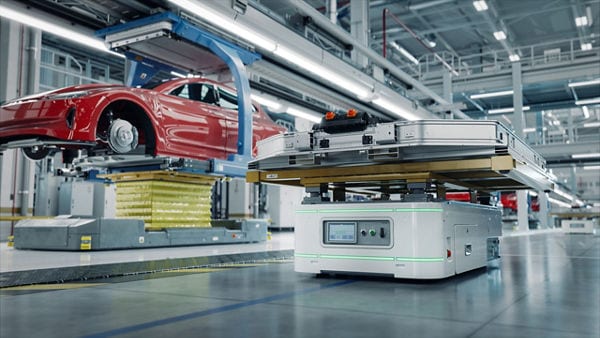 A modern automotive assembly line with red cars being assembled.