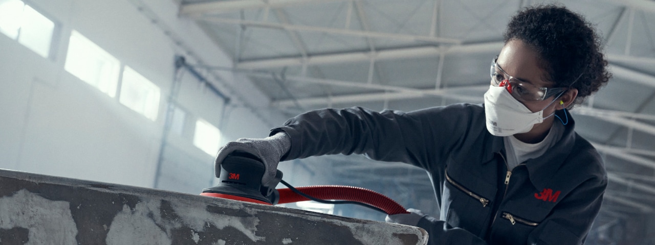 Photo of a technician sanding surface with 3M Xtract sander and personal protective equipment