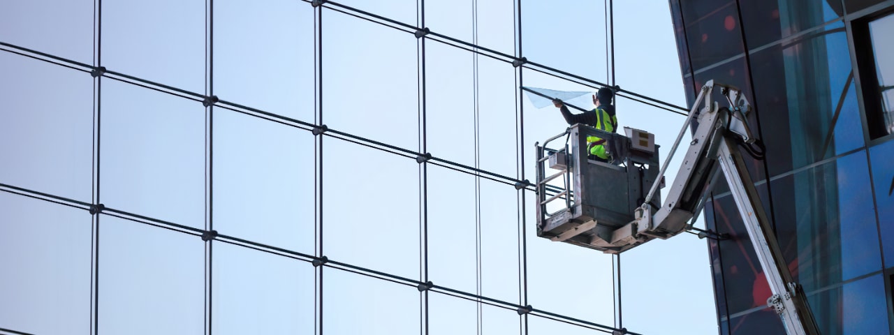 Photo of a technician installing 3M energy efficiency film on the windows of a commercial building