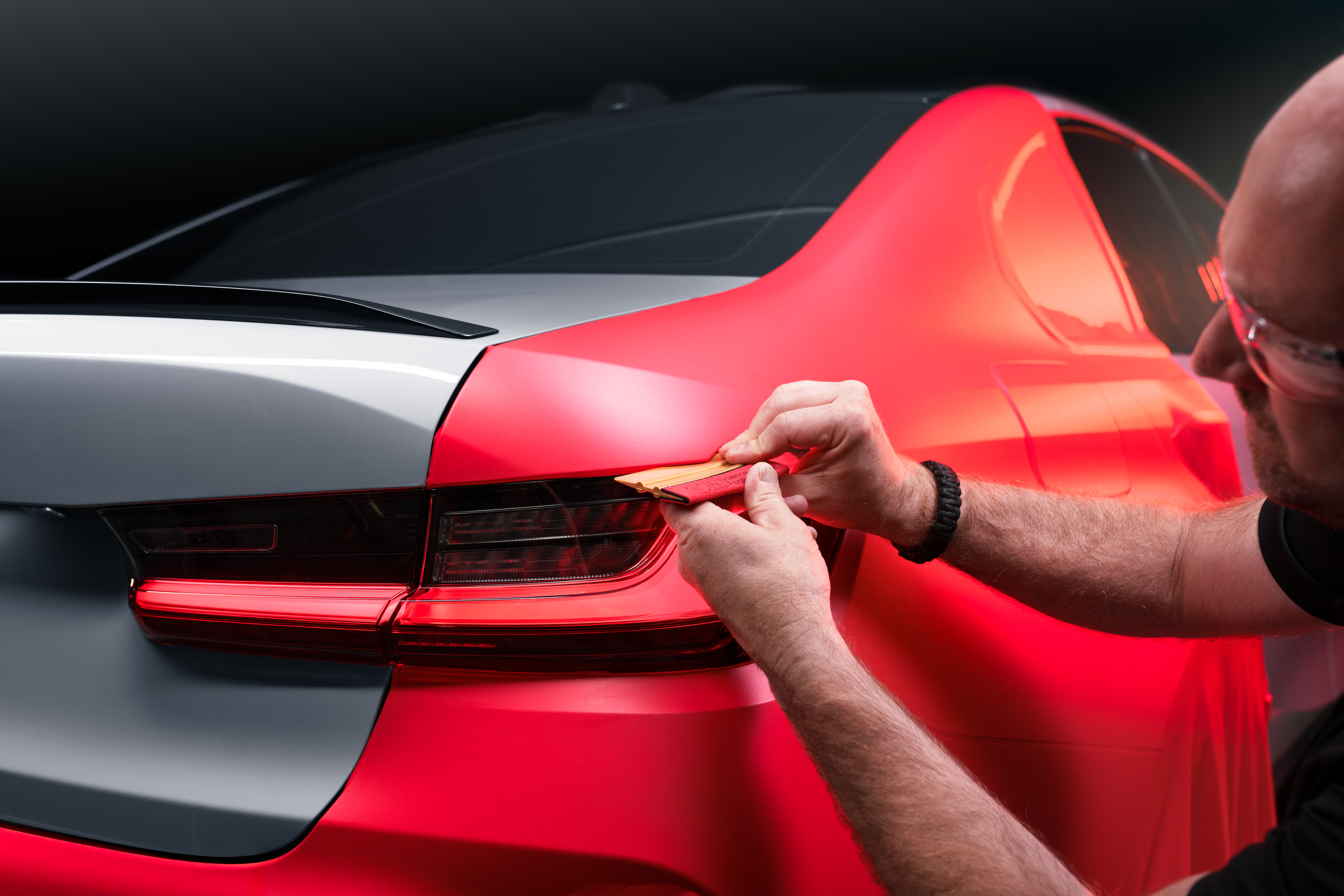 Applying red wrap to the fender of a car.