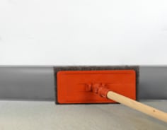 Scrubbing vinyl baseboard with brown pad