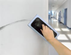 Removing scuff marks on hospital wall with erasing pad