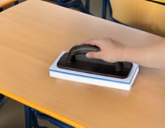 Cleaning laminate desk in high school with erasing pad