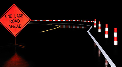 Road work zone at night with wet pavement showing retroreflective signs, cones, and road stripes.
  Road work zone at night, signs and cones reflect on wet pavement, white and yellow road stripes show wet retroreflectivity