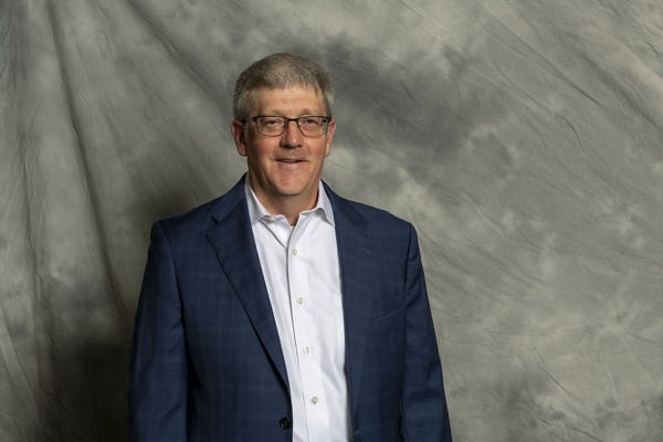 Portrait of David Hays against gray textured cloth background.