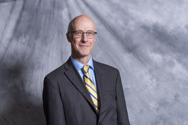 Portrait of Matthew Atkinson against gray textured cloth background.