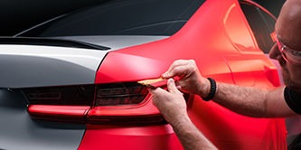  Applying red wrap to the fender of a car.