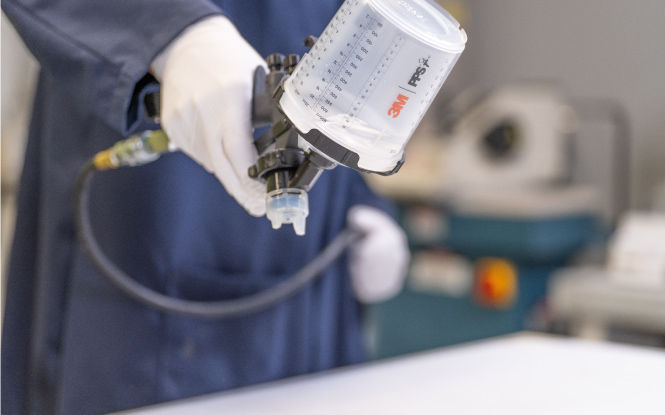 Spray gun applying a pre-treatment coating to a surface.
