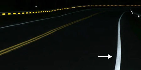 Winding road at night, a bright reflective white road line is highlighted.
