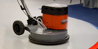 A portable floor scrubber cleaning a coated floor.