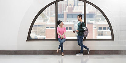 Two people conversing in front of a window and shiny floor